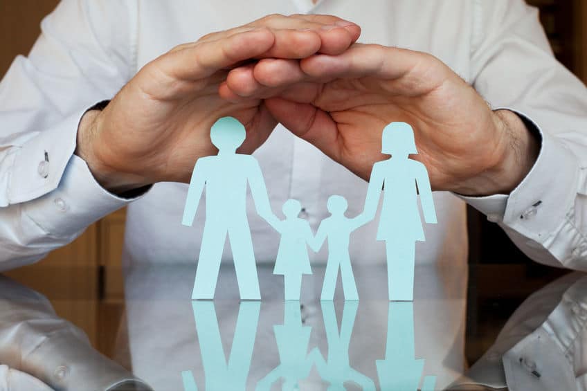 paper cutout of family with mans hands over it