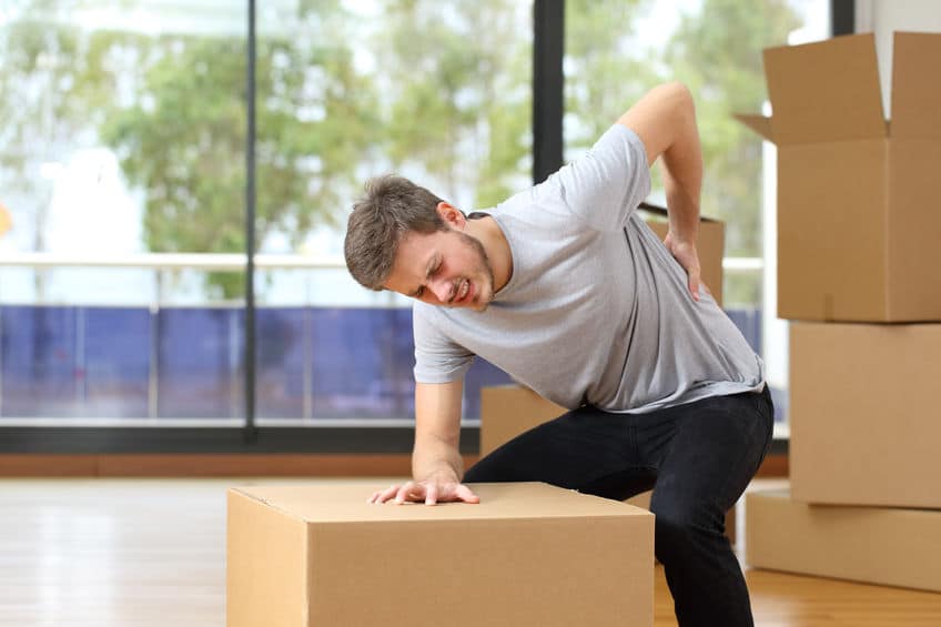 Man holding his back in pain lifting boxes