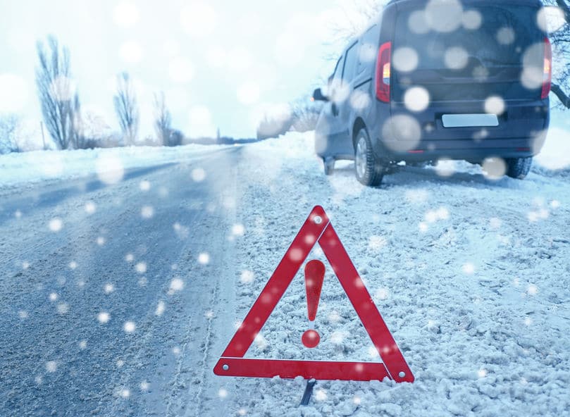 Hazard sign on side of snowy road with black van
