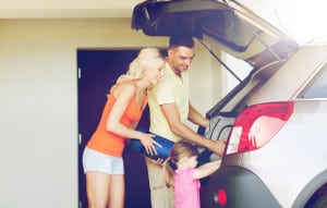 happy family packing things to car at home parking